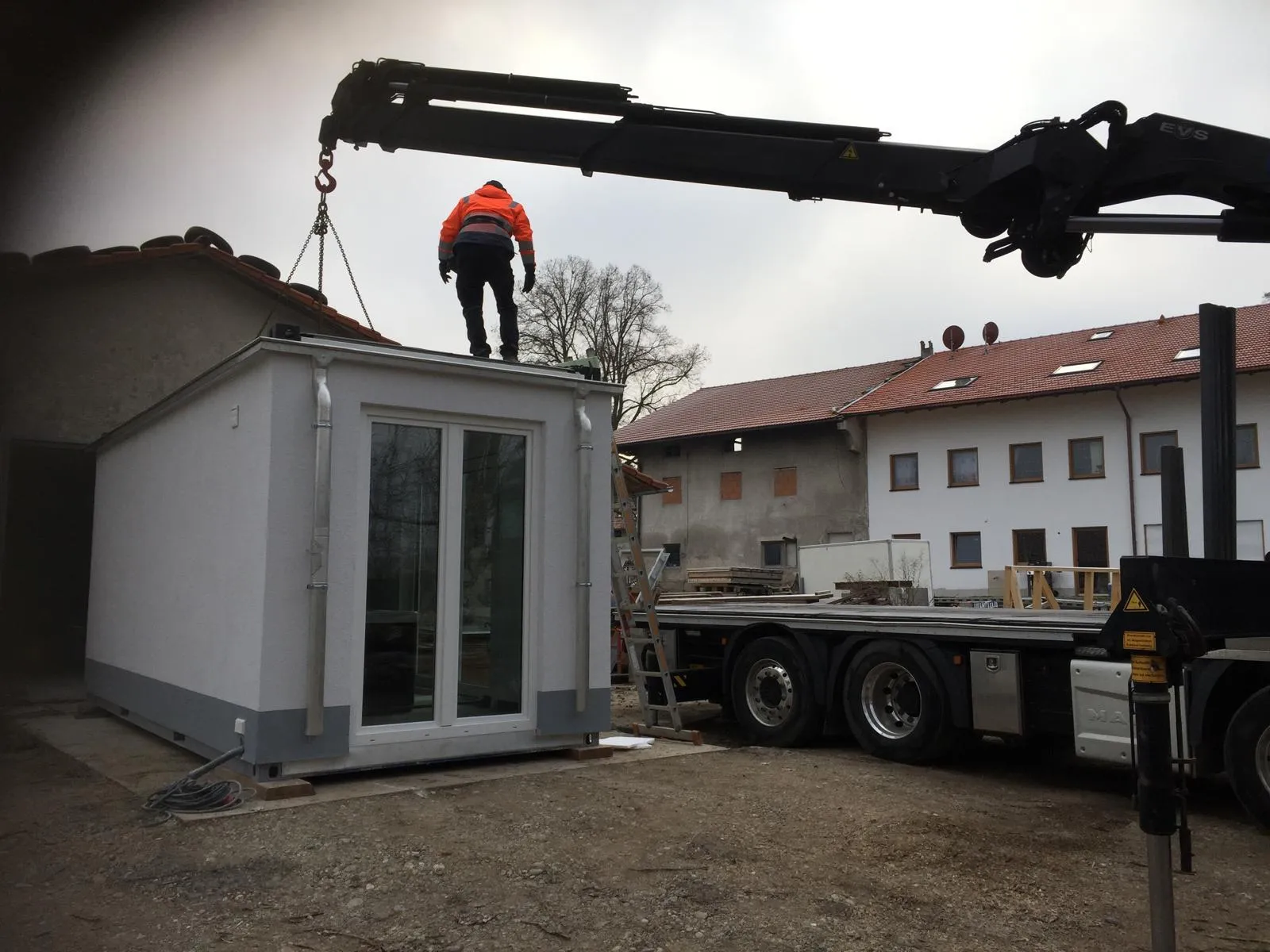 Kran hebt ein Mod-System-Modul auf einen Tieflader